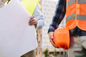 Commercial remodeling contractors holding a plan and hard hat.