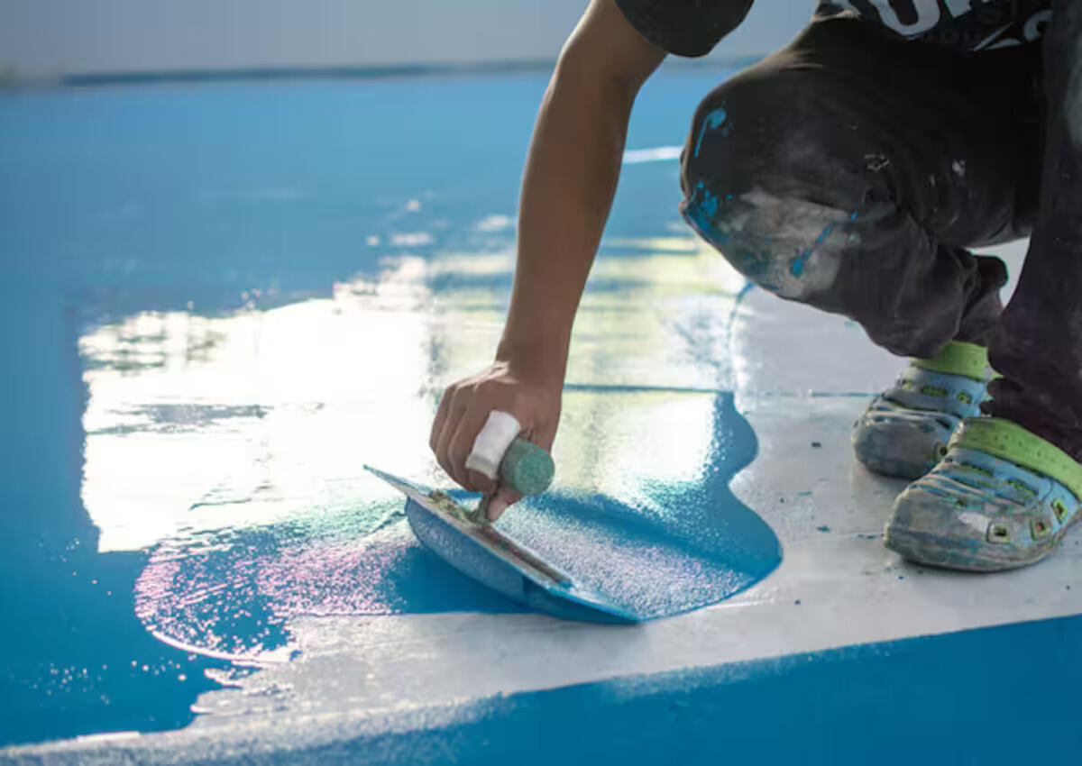 A worker applying waterproofing to the floor