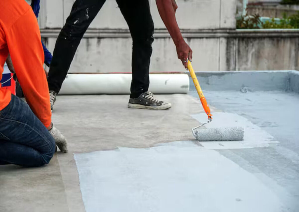 Workers applying waterproofing to a commercial building under construction