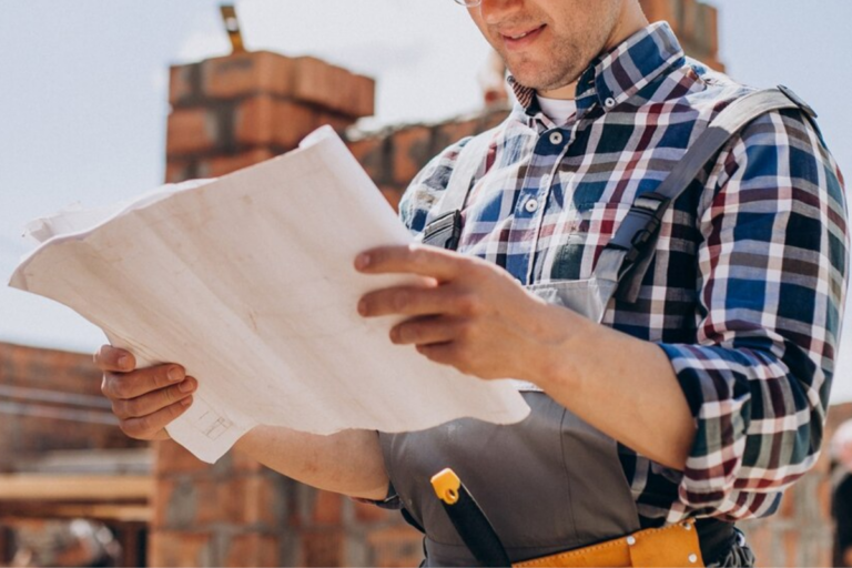 A commercial building contractor reading construction plans with a construction site in the background