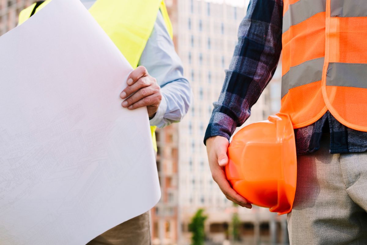 Workers holding the plans and hard hats