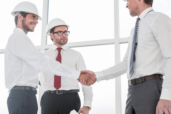 A business owner shaking hands with the contractors chosen to handle the commercial building remodel project